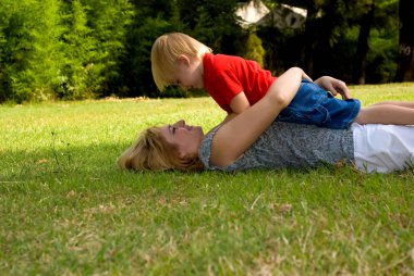 mutlu anne ve oğlu parkta çim üzerinde yalan