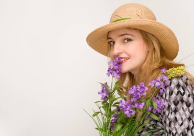 ışık stüdyo arka plan üzerinde poz çiçek tutan hasır şapka giyen güzel gülümseyen kadın