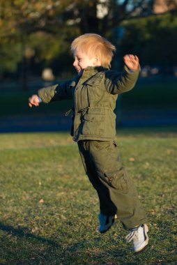 sevimli küçük çocuk eğleniyor yeşil çimenlerin üzerinde atlama