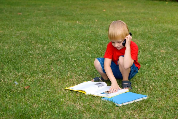 Söt Liten Pojke Sitter Grönt Gräs Med Böcker Och Pratar — Stockfoto