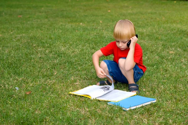 Roztomilý Malý Chlapec Sedí Zelené Trávě Knihami Mluví Mobilní Telefon — Stock fotografie