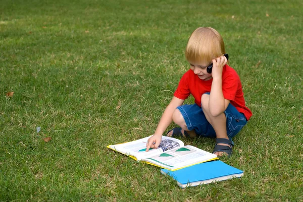 Roztomilý Malý Chlapec Sedí Zelené Trávě Knihami Mluví Mobilní Telefon — Stock fotografie