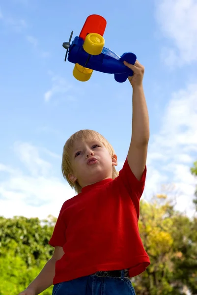快乐的小男孩在绿色公园里玩彩色飞机 — 图库照片