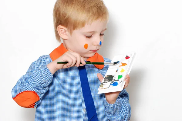 带彩色油漆斑点的小男孩拿着刷子做鬼脸 — 图库照片