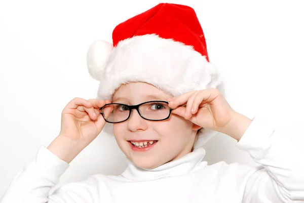 赤いサンタ帽子と白い背景で隔離の眼鏡を身に着けている笑みを浮かべて少年 — ストック写真