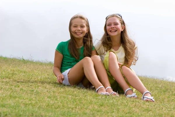Дві Молоді Дівчата Довгим Волоссям Розважаються Сидячи Зеленій Траві Відкритому — стокове фото