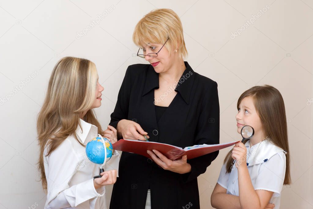 teacher pointing on copybook and talking with pupils at school