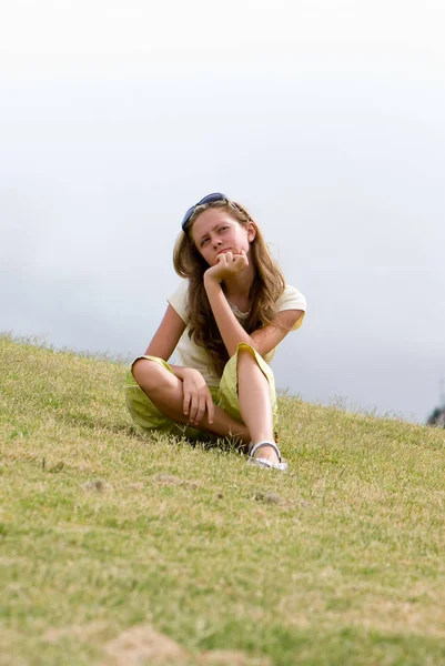 長い髪とサングラスの緑の草の上に座ってかなり十代の少女 — ストック写真