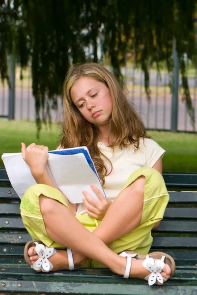 可爱的少女阅读书坐在长椅上的绿色公园 — 图库照片