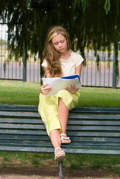 緑豊かな公園 完全な長さでベンチに座って本を読んでかわいい十代の少女 — ストック写真