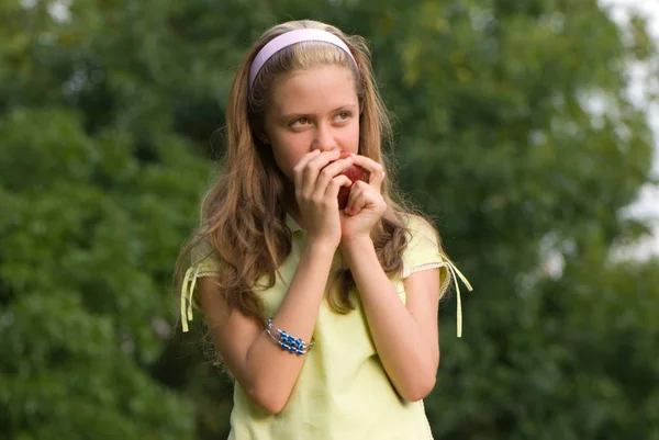 緑豊かな公園で赤いリンゴを立ち食いかわいい十代の少女 — ストック写真