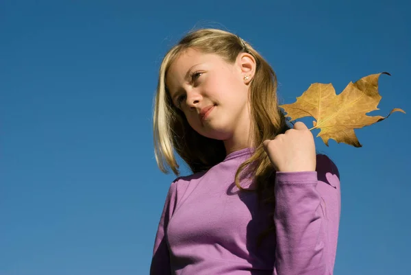 Schöne Teenager Mädchen Halten Herbstblatt Steht Auf Blauem Himmel Hintergrund — Stockfoto