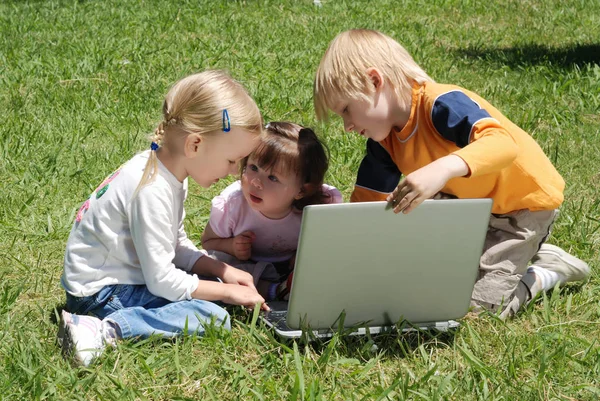 可爱的小孩子一起在公园里使用笔记本电脑 — 图库照片
