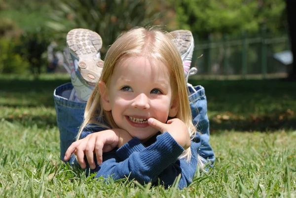 公園の草の上に横たわっている愛らしい小さな女の子の肖像画 — ストック写真