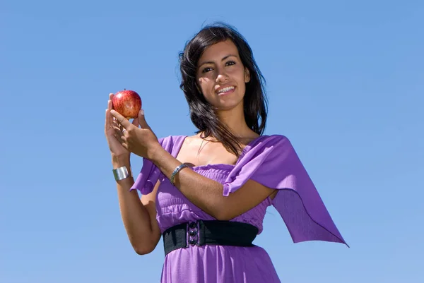 美丽的年轻女子吃苹果在蓝天前 — 图库照片