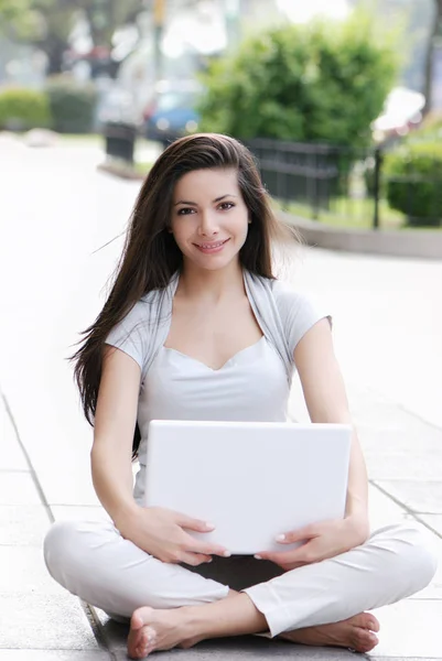 美丽的年轻女子在街上使用笔记本电脑 — 图库照片