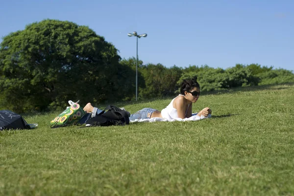 美丽的年轻女子在公园的绿色草地上放松 — 图库照片