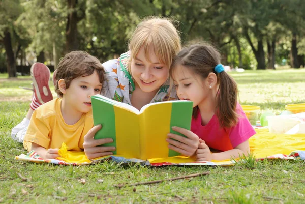 Genç Bir Kadın Çocuklarla Parkta Vakit Geçirip Kitap Okuyor — Stok fotoğraf