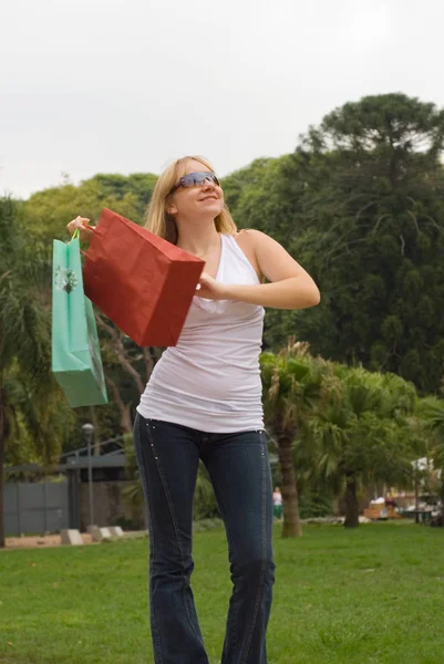 公園でカラフルなショッピングバッグと美しい若い女性 — ストック写真