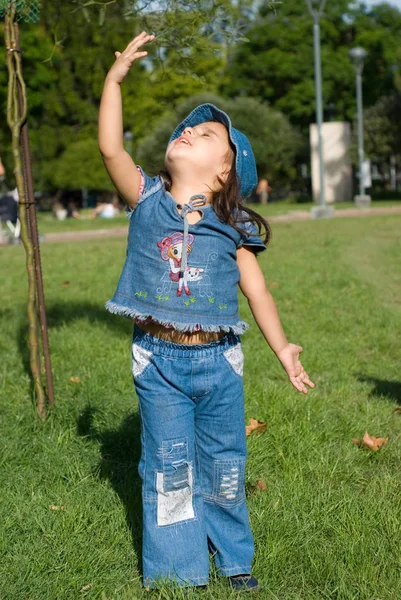可爱的小女孩在绿色草地上牛仔布 — 图库照片