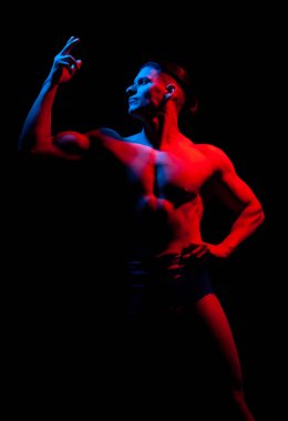 siyah arka plan üzerinde kırmızı ve mavi ışık boyalı çok kaslı yakışıklı atletik adam 