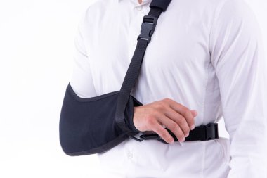 Beyaz arka planda kol askısı takan kırık eli olan adam 