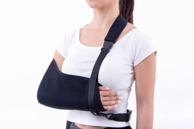 Beyaz arka planda kol askısı takan kırık eli olan kadın 