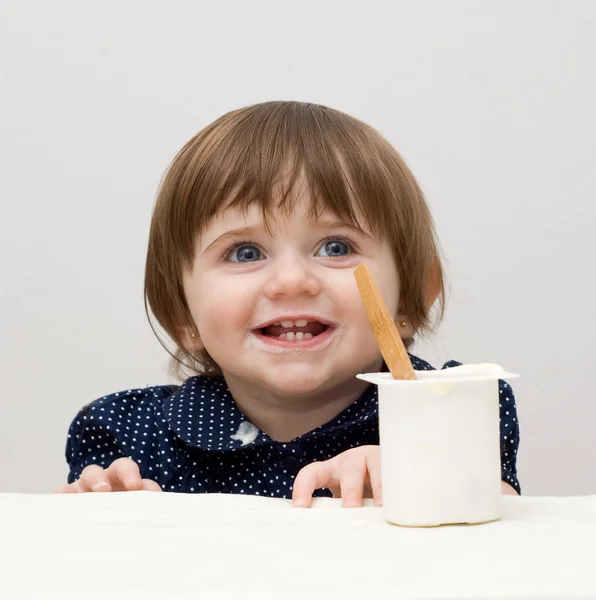 穿着深蓝色T恤的小女孩在白色背景上吃酸奶的肖像 — 图库照片