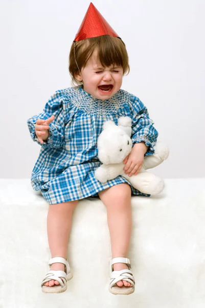 おもちゃを持ち 白い背景に泣いている綿のドレスを着た少女の肖像画 — ストック写真