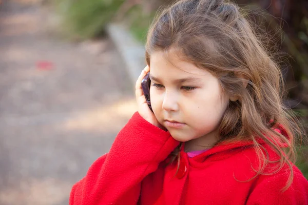 Κορίτσι με κόκκινο με το κινητό στο πάρκο — Φωτογραφία Αρχείου