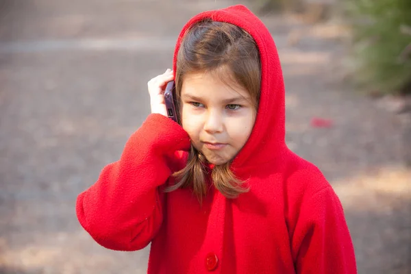 Girl in red with mobile in park — Stock Photo, Image
