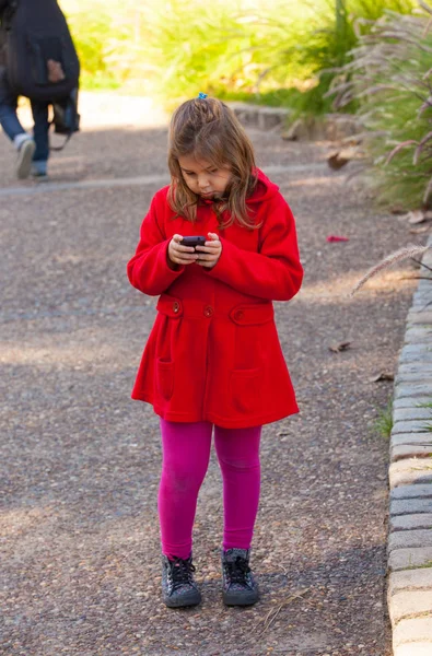 Chica en rojo con móvil en el parque — Foto de Stock