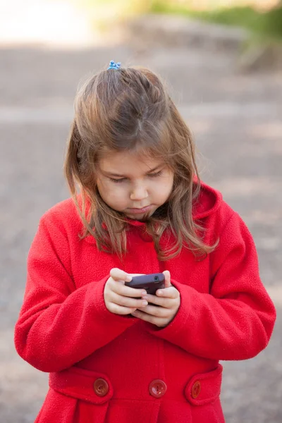 Κορίτσι με κόκκινο με το κινητό στο πάρκο — Φωτογραφία Αρχείου