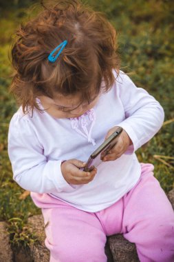 Parkta cep telefonu olan bebek