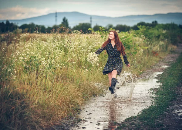 Girl running along the rural road with a bouquet of wild flowers
