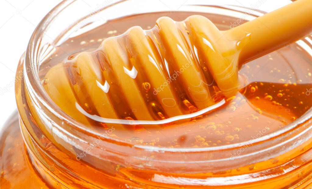 golden bee honey in a glass jar and honey dipper