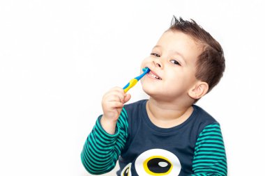 Dişlerini fırçalayan küçük bir çocuk gülümsüyor.