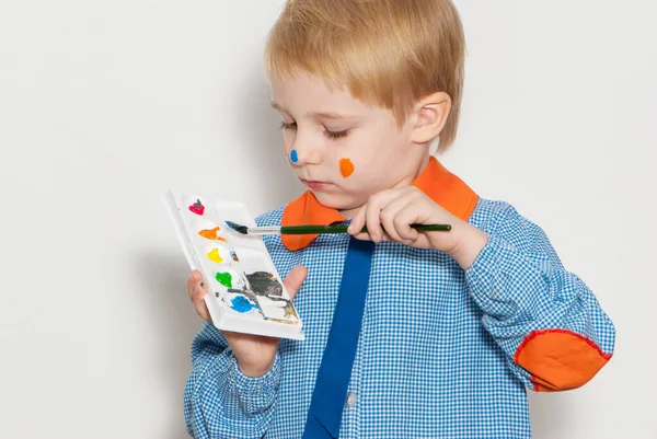 絵具で覆われたブラシで面白い顔を作る小さな男の子 — ストック写真