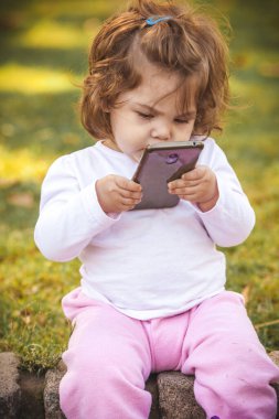 Parkta cep telefonu olan bebek 