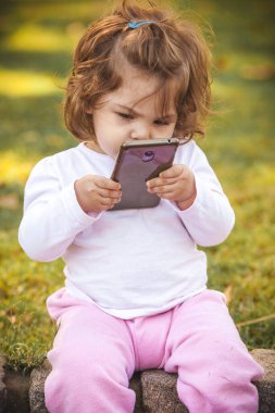 Parkta cep telefonu olan bebek 