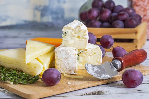 木の板に木製のテーブルのブドウとおいしいチーズ — ストック写真