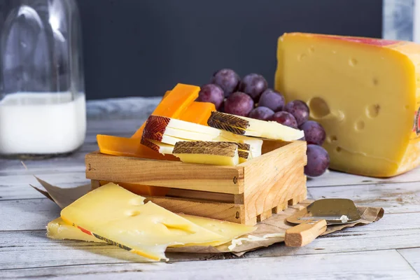木の板に木製のテーブルのブドウとおいしいチーズ — ストック写真
