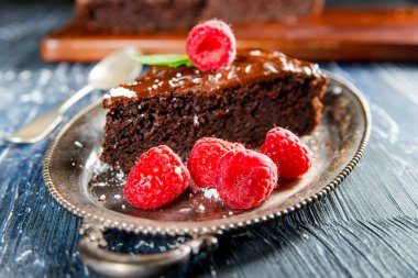 Tabağında ahududu olan çikolatalı pasta.