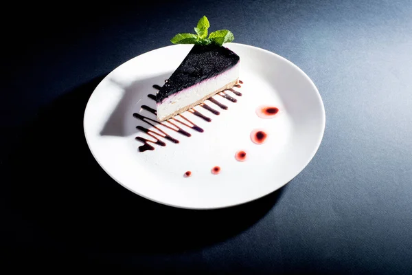 slice of cheesecake on  platter on  black background