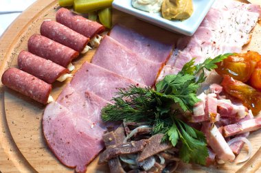 Ahşap tezgahta çeşitli etleri kesiyor.