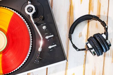 Yüksek çözünürlüklü müzik sehpası, kırmızı ve turuncu plaklar ve kırsal ahşap üzerinde siyah kulaklıklar.