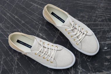 Tommy Hilfiger kumaşlı kaldırımda spor ayakkabıları dikişli logo ve nötr tonlar ile günlük şehir tarzını yansıtıyor..