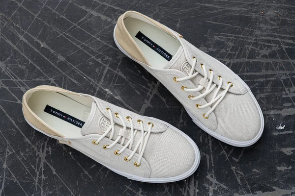 Tommy Hilfiger kumaşlı kaldırımda spor ayakkabıları dikişli logo ve nötr tonlar ile günlük şehir tarzını yansıtıyor..