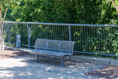 Şehir Park Ayarları 'nda Yeşil Çalıların yanındaki Boş Metal Benç