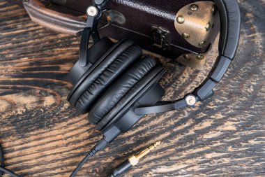 Profesyonel kulaklıklara yakın çekim ve ahşap dokuda kriko. Metalik detaylar ve sarmalanmış kabloyla ses aksesuarını stile et,